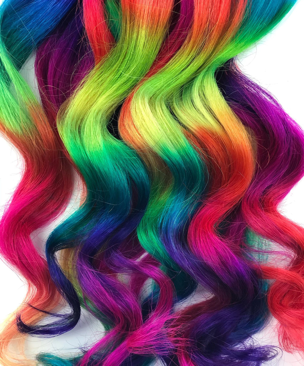 Vibrant rainbow curly clip-in hair extensions with neon pink, purple, teal, green, yellow, and orange ombre waves.